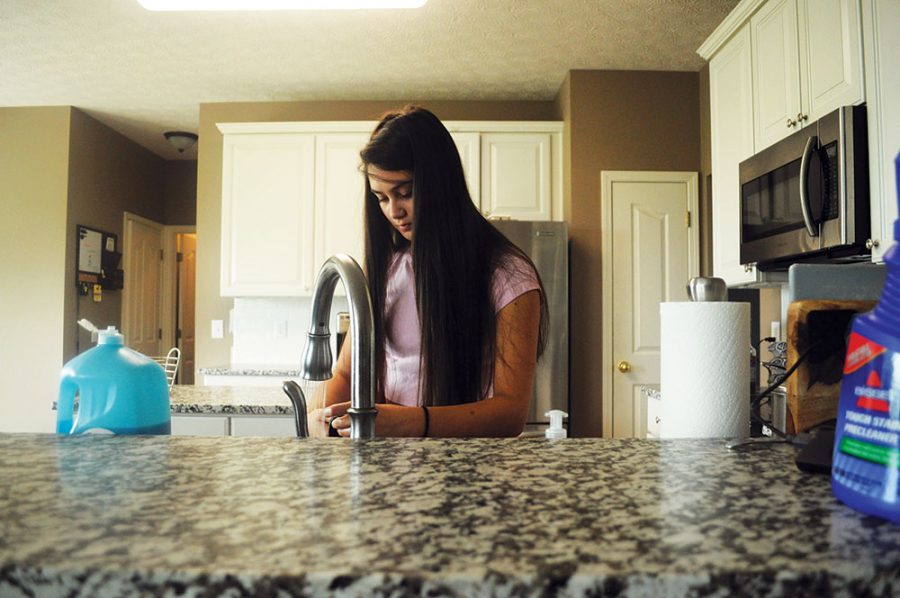 Junior Megan Fortier washes the dishes she used to eat lunch. She said living with one parent gave her more responsibilities at home. 